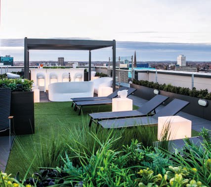 Roof terrace lounge seating with Coventry skyline at dusk
