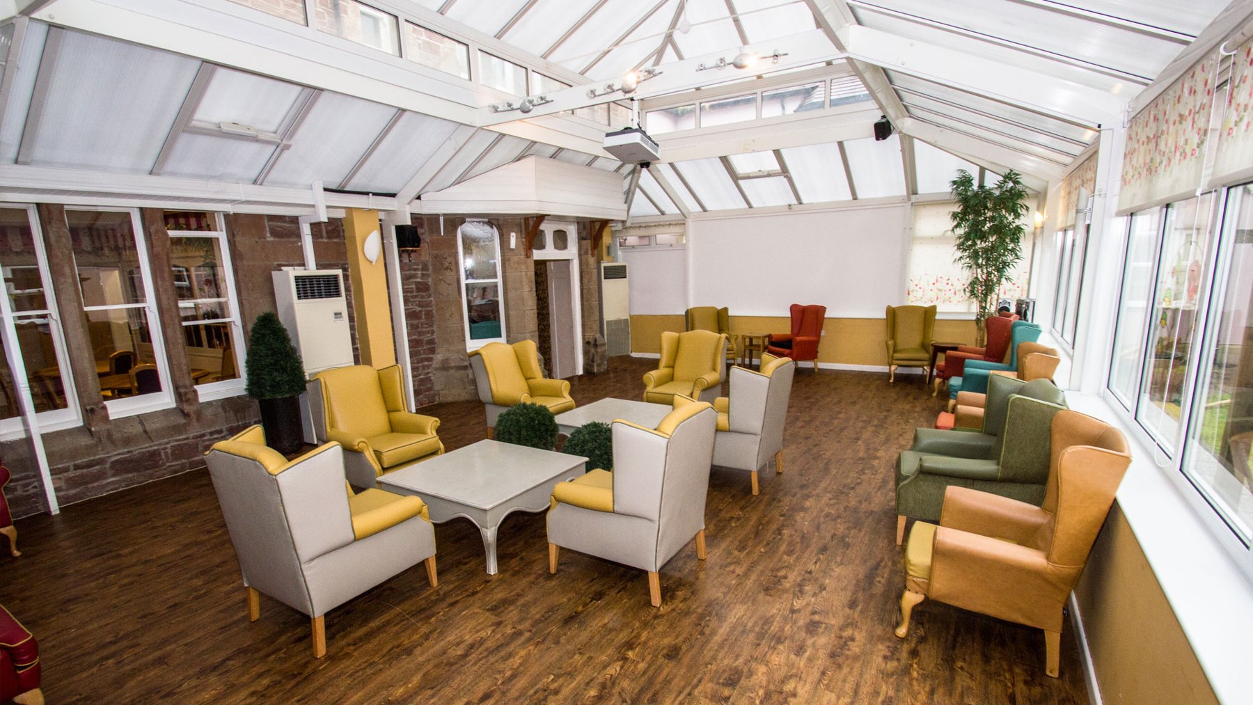 Bright conservatory lounge with armchairs and garden views