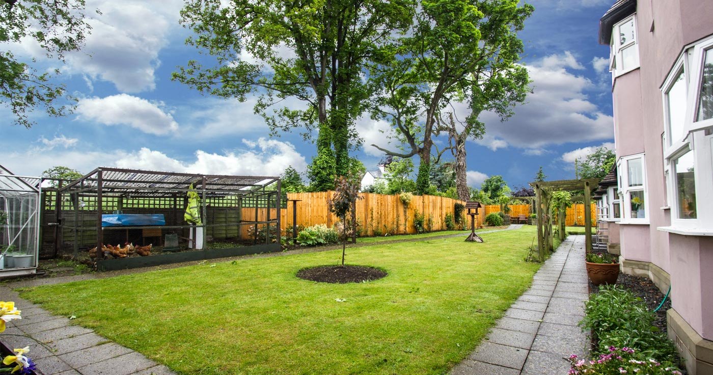 Landscaped lawned garden with mature trees at an established care home